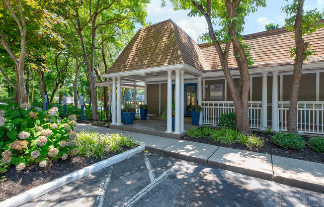 the front of a white house with trees and a porch