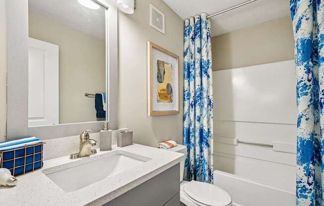 A bathroom with a white sink, toilet, and shower curtain.