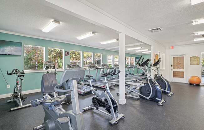 A gym with a variety of exercise equipment including treadmills, stationary bikes, and weight machines.