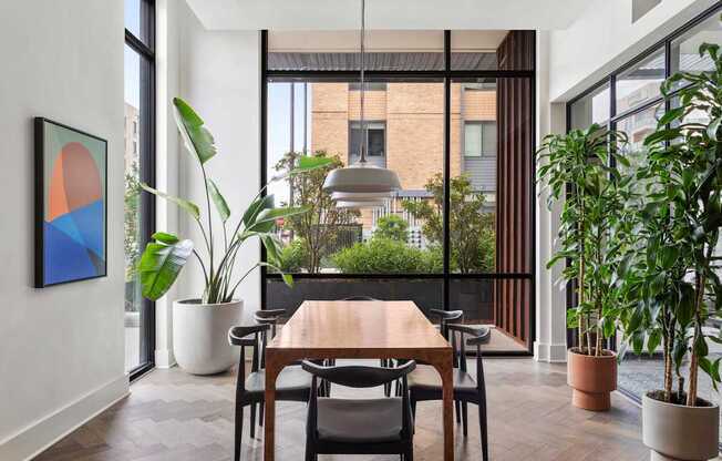 A dining room with a table and chairs and a potted plant.