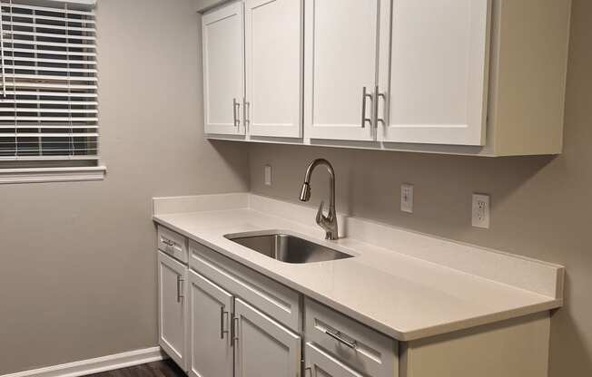 a kitchen with white cabinets and a sink and a window