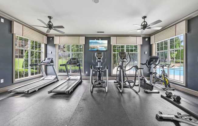 A spacious gym with treadmills, exercise bikes, and a television.