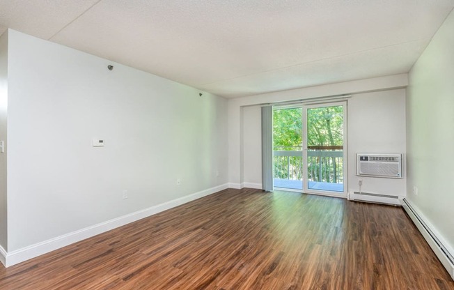 an empty living room with wood floors and a door to a balcony