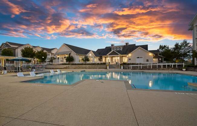 a swimming pool at sunset with houses in the background