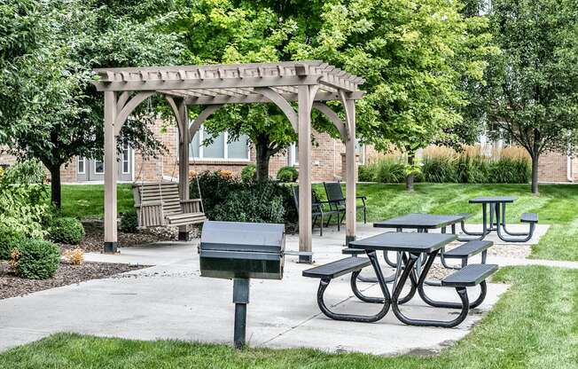 a picnic area with picnic tables and a grill at Legacy Commons Apartments in Omaha, NE
