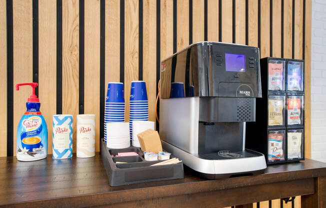 a coffee maker on a table with coffee cups and a napkin dispenser next at Presidio Palms Apartments, Arizona