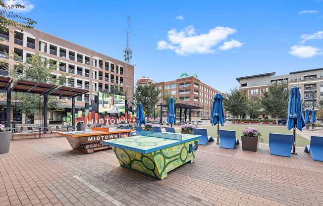 a park with a ping pong table and umbrellas in a city