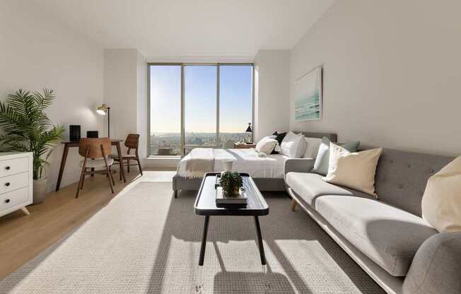 a living room with a couch and a table and a large window at The Paxton, Brooklyn, 11201