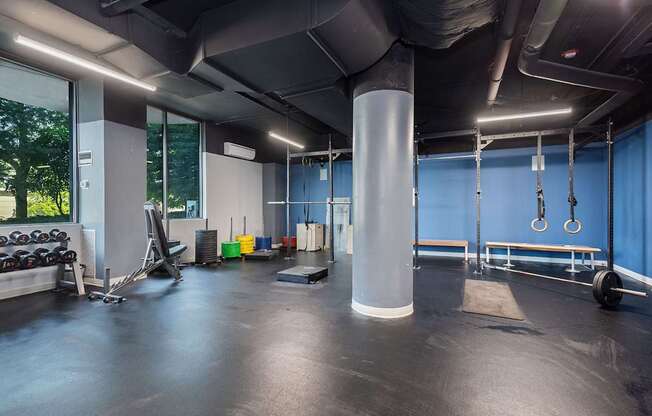 A gym with a variety of equipment including dumbbells, weight plates, and a bench.