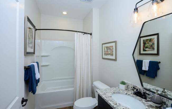 A bathroom with a white toilet, a sink, a bathtub, and a mirror.