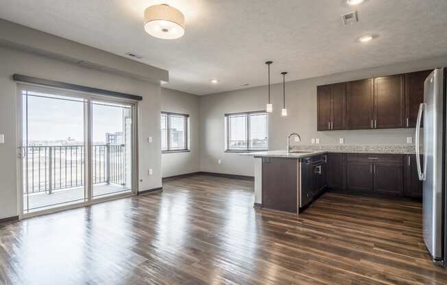 View from living room of kitchen and dining room with hardwood-style floors and balcony at 360 at Jordan West best new apartments West Des Moines IA 50266