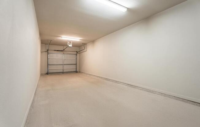 A long, narrow, empty room with a white ceiling and walls, and a metal gate in the middle.