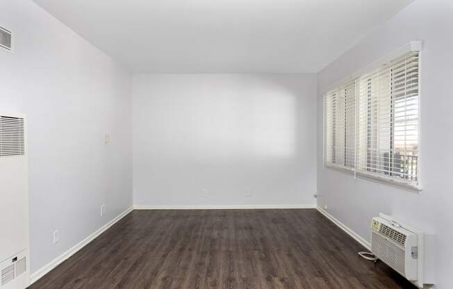 an empty room with white walls and wood floors and a window