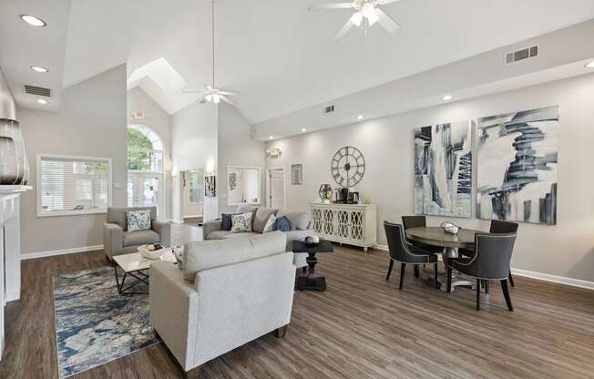A living room with a white couch, a black dining table, and a ceiling fan.