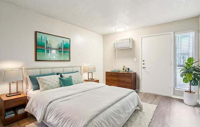 A bedroom with a large bed, a nightstand with a lamp, and a painting on the wall.