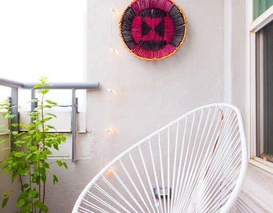 a white chair on a balcony with a fan