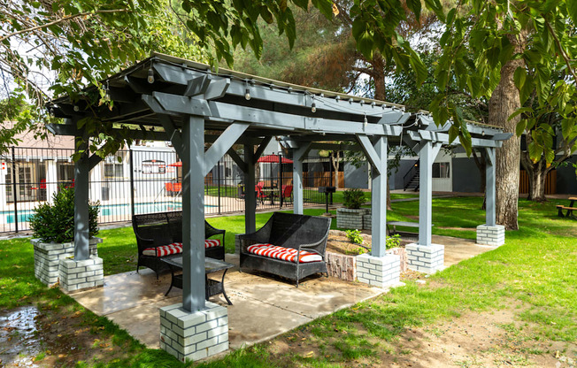 A gazebo with two red and white striped chairs sits in a grassy area.