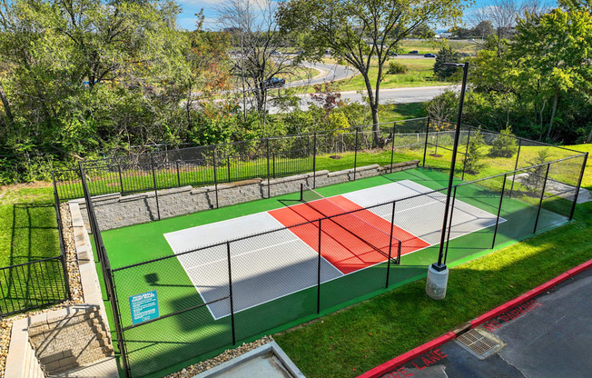 a tennis court with a fence around it in a park