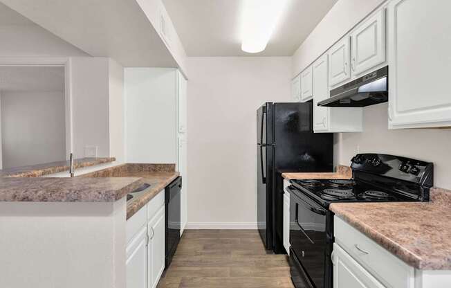 A kitchen with black appliances and white cabinets at Urban WalkApartments on 6th Avenue, Arizona