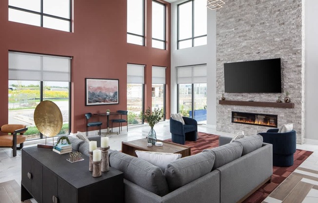A modern living room with a grey sofa, a fireplace, and a large window.