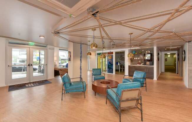  Leasing Office with Hardwood Inspired Floor, Blue Sofa Chairs, Hanging Ceiling Lights and Exit Door