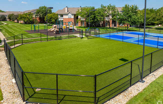 A black fence surrounds a green lawn and a blue pool.