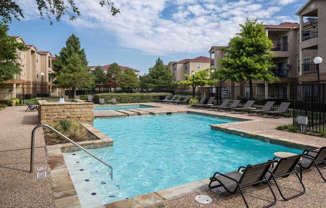 A swimming pool surrounded by chairs and trees.