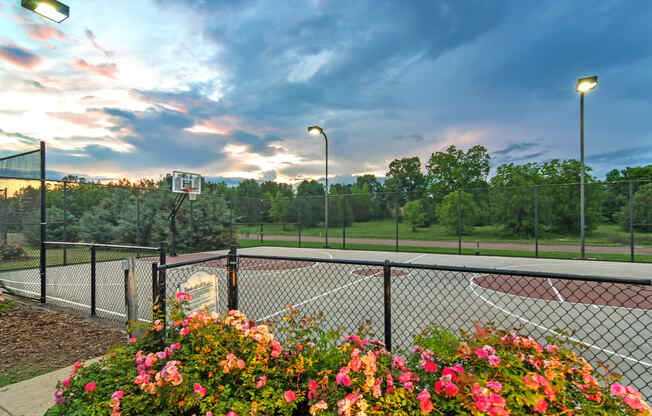 a basketball court at sunset with flowers and a fence at Avalon Apartment Homes, Starkville