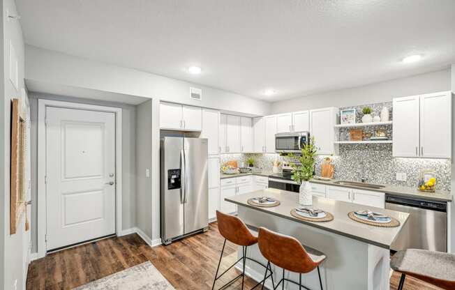 a kitchen with stainless steel appliances and a island with three chairs