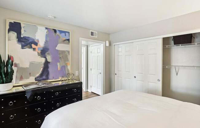 A bedroom with a large bed and a painting on the wall.