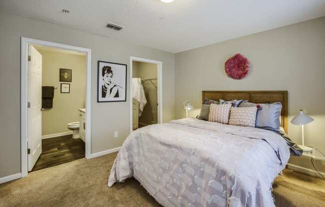 a bedroom with a large bed and a bathroom in the background