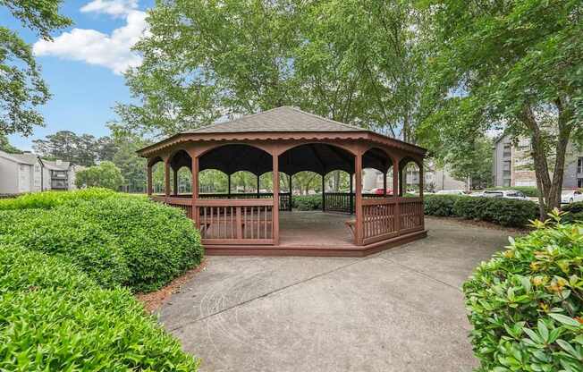 A gazebo surrounded by green bushes and trees.