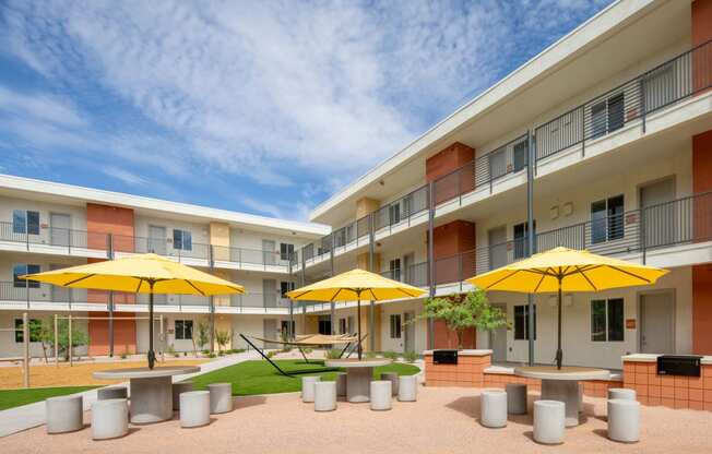 a courtyard with tables and chairs and yellow umbrellas