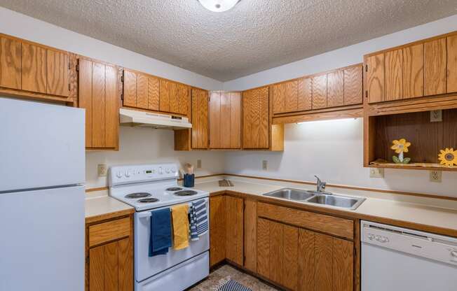 a kitchen with white appliances and wooden cabinets. Fargo, ND Crescent Park Apartments