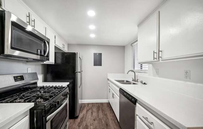 an empty kitchen with white cabinets and stainless steel appliances