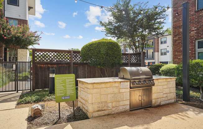 a barbecue grill is in front of a fence and a building