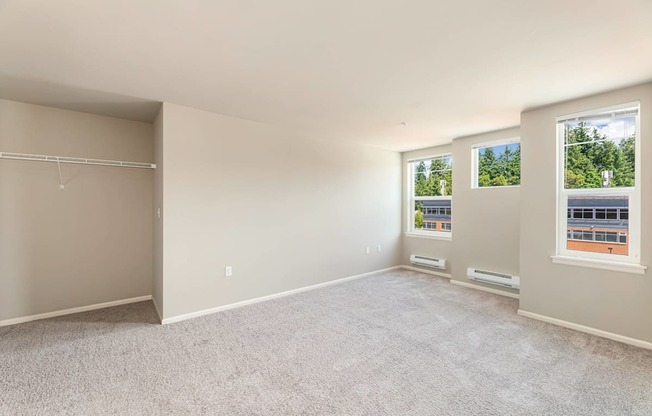 Empty room with carpeted floor and two windows.