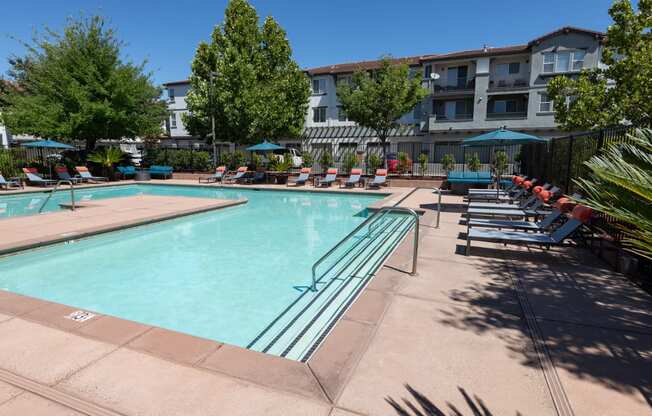 expansive pool with surrounding lounge chairs and umbrellas