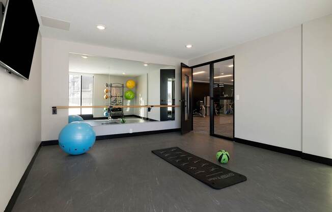 A blue exercise ball sits on a mat in a room with a mirrored wall.