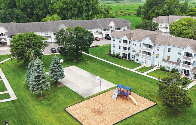 A playground with a slide and a sandbox is surrounded by apartment buildings.