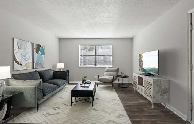 Element at 4411 Macon Apartments A living room with a grey couch, a coffee table, a television, and a window with blinds.