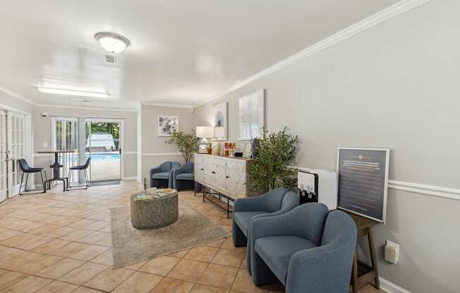 a living room with chairs and a table and a door to a pool
