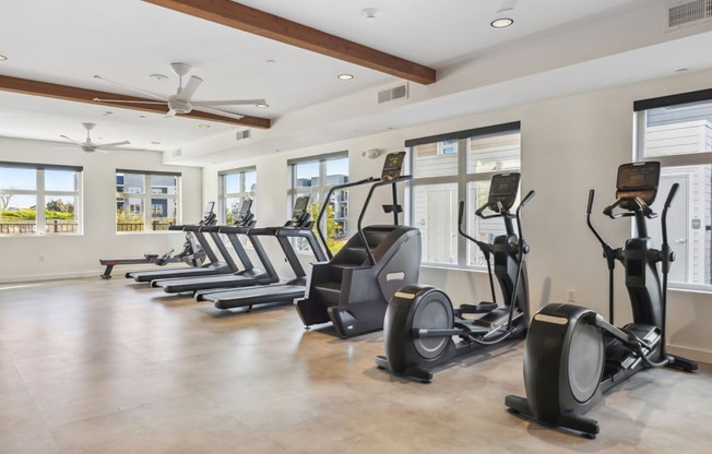 a gym with cardio ellipticals and windows in a house