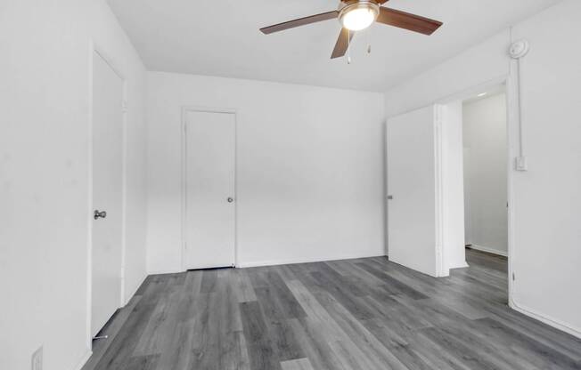 a living room with white walls and a ceiling fan