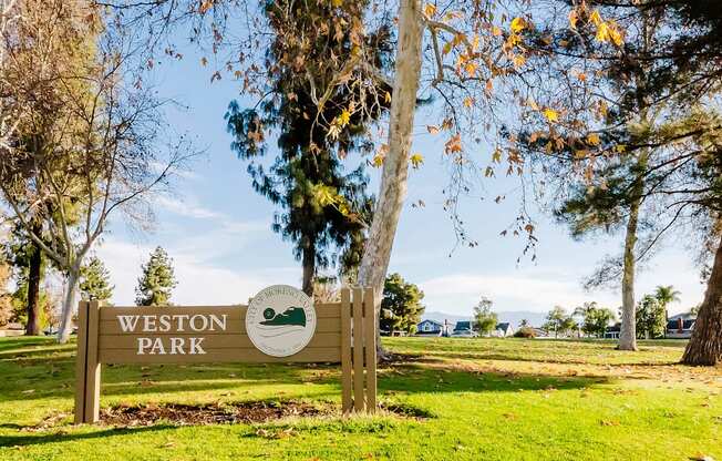 A sign that says Weston Park is in front of a tree.