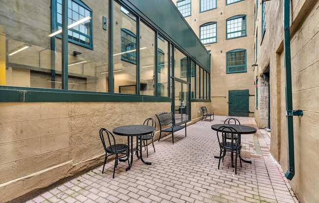 A patio with tables and chairs is surrounded by a wall.