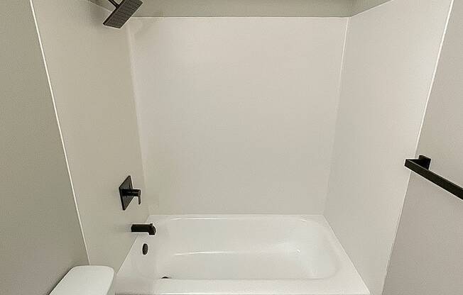 A white toilet sits next to a white bathtub in a small bathroom.