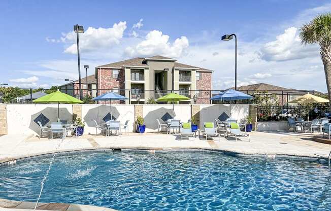 A pool area with a building in the background and lounge chairs around the pool at Canebrake Apartment Homes in Shreveport, LA