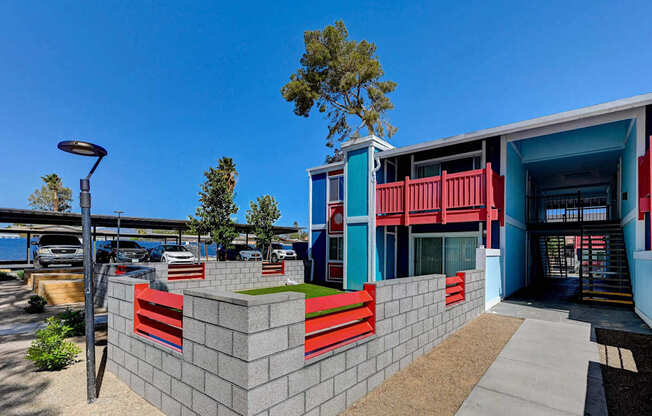 A modern building with a blue and red facade and a green tree in front.