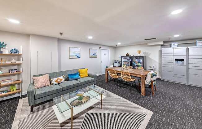 Room with a grey couch, a glass coffee table, and a wooden dining table with chairs.